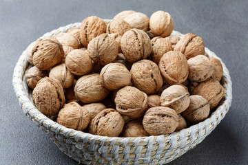 Walnuts and nut kernels in a basket on a concrete table