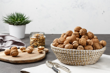 Walnuts and nut kernels in a basket with a nutcreacker on a concrete kitchen table, light-filled space