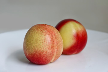 Two delicious ripe juicy nectarines on a white plate. Healthy fruits, vitamins.