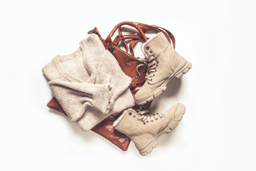 Female autumn winter cozy look  flat lying. Warm boots, sweater, bag on a light gray background. Concept of autumn fashion and trends.