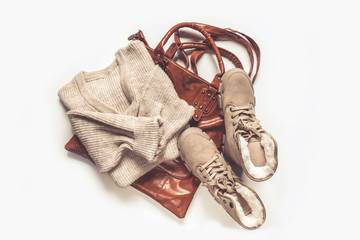 Female autumn winter cozy look  flat lying. Warm boots, sweater, bag on a light gray background. Concept of autumn fashion and trends.