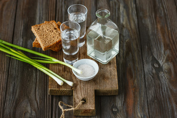 Vodka with green onion, bread toast and salt on wooden background. Alcohol pure craft drink and traditional snack. Negative space. Celebrating food and delicious.
