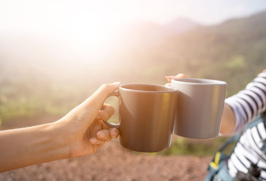 Closeup hands holding coffee cup drinking coffee or tea and nature background.Hands clink hot coffee mug outdoor in the morning , friends enjoy drinking together cheers for two cup in morning