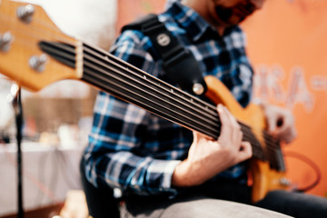 Photo of musician playng on six string fretless bass guitar on the street in front of people.