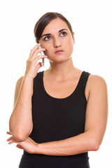 Studio shot of beautiful woman talking on mobile phone while thinking