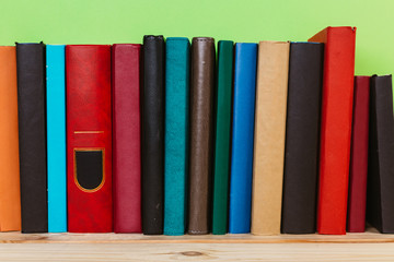 Naklejka premium Simple composition of many hardback books, raw of books on wooden table and light green background