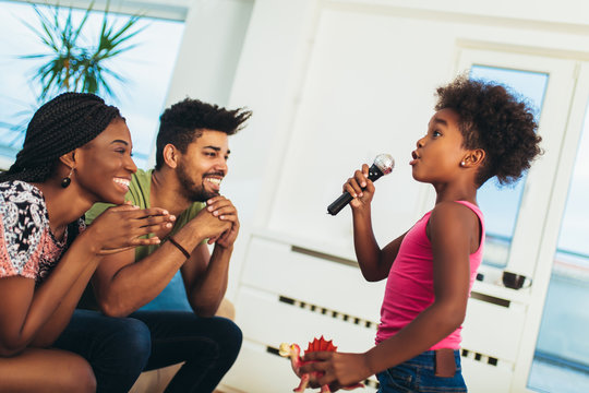 African american family enjoy singing karaoke at home, having fun.
