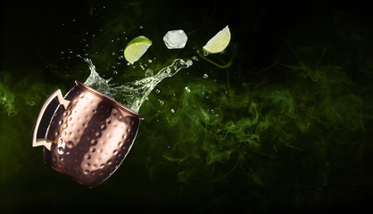 lime and ice falling out of a splashing moscow mule on smoky background