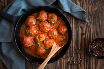 Homemade meatballs with tomato sauce and parsley in a frying pan