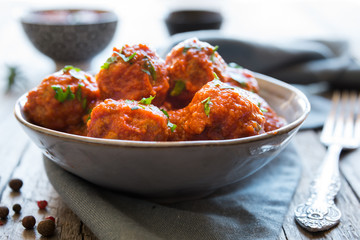 Homemade meatballs with tomato sauce and parsley in a bowl