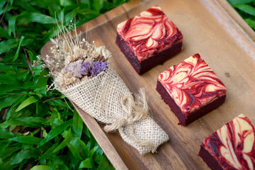 Red velvet cream cheese brownies on wooden plate