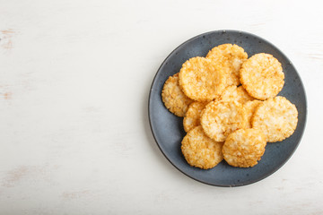 Traditional japanese rice chips cookies with honey and soy sauce on a blue ceramic plate on a white wooden background. Top view.