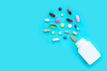 Colorful tablets with capsules and pills on blue background.