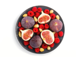 Fresh figs, strawberries and raspberries on blue ceramic plate isolated on white background. top view