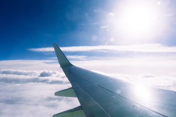 Fototapeta premium Wing of an airplane flying above the clouds