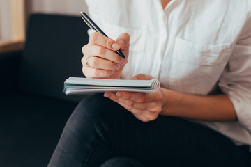 Beautiful female hands hold an open book or magazine in the room