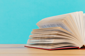A simple composition of many hardback books, raw books on a wooden table and a bright blue background