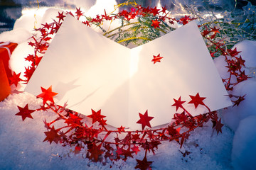 An open Christmas Card template on a bed of snow, red star-glitter and green juniper.