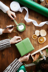 Close-up of mother and daughter working at the table together they decorating present with ribbon for holiday
