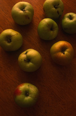 Top view of ripe juicy garden apples on wooden background in warm golden light, vertical image