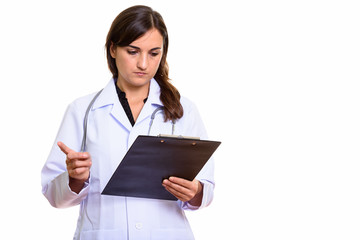 Studio shot of beautiful woman doctor reading on clipboard