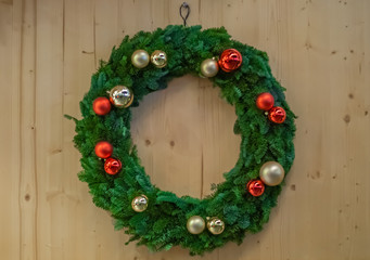 Christmas wreath with baubles on a wooden wall