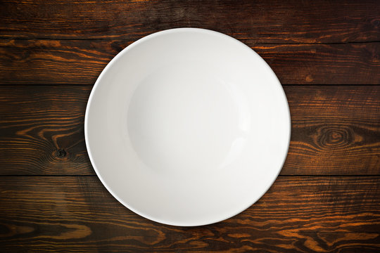 top view of empty white plate isolated on wood table