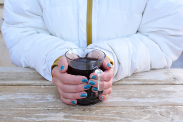 Glass of hot, mulled red vine in young girl's hands