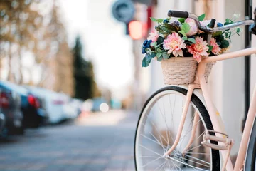 Door stickers Bike White bicycle with basket of flowers standing near the door on the street in city.