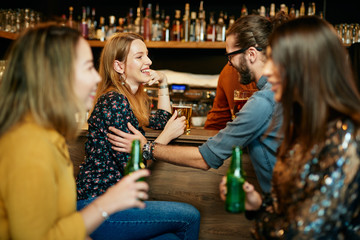 Group of friends drinking beer, chatting and having good time at pub. Night out.