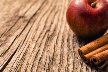 Christmas decoration macro: Red apple, cinnamon sticks on rustic wooden background, retro style