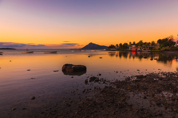 Sea with fishing boats and town at sunset time in Mauritius.