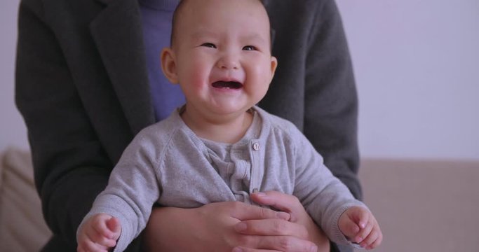 Close up happy lovely asian baby girl smile and laughs sitting on father's lap adorable newborn baby infant at home