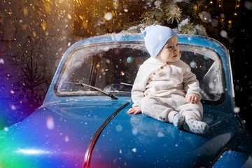 The kid is sitting in a blue car that orders a Christmas tree. Christmas concept. New year concept