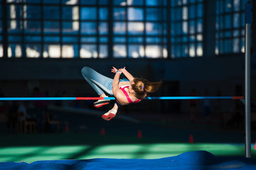 Woman jumping over bar at athletics meeting