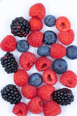 blueberries raspberries blackberries on a white background overhead macro shot