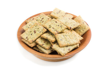 Small bread chips cookies with seeds in a wooden bowl isolated on white background. side view