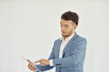 Young business man in a suit is playing a tablet