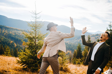 Two men clapping each other's hand on a background of mountains