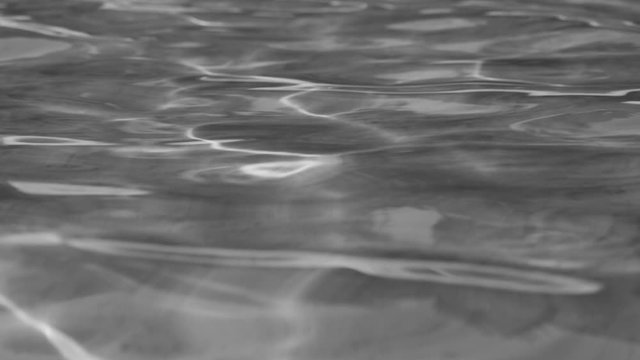 Closeup view of texture of calm sunny water of sea. Black and white natural video background. Real time full hd footage.
