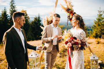 Newlyweds exchange rings during their beautiful wedding ceremony outdoors. Wedding ceremony in...
