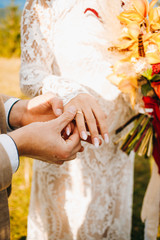 Newlyweds exchange rings during their beautiful wedding ceremony outdoors.