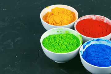 Indian Holi festival colours in small  bowls on dark background
