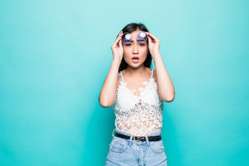Young pretty asian woman surprised take out sunglasses isolated on green background