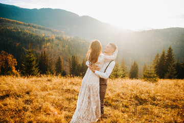 Amazing groom hugging happy bride in sun light, romantic moment, boho wedding couple, luxury ceremony at mountains with amazing view © Yuliia