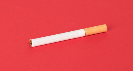 Single cigarette isolated on red background