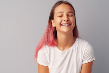 Young girl teenager with pink hair happy and smiling over gray background