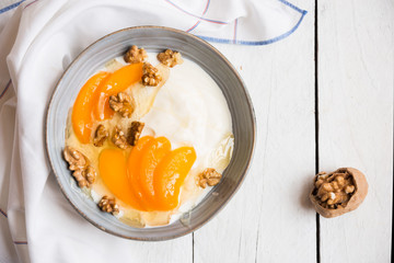 Yogurt with peach, nuts and honey in a bowl