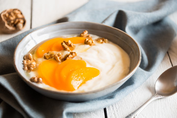 Yogurt with peach, nuts and honey in a bowl