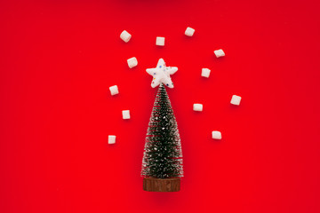 Christmas tree and marshmallow as snowflakes on the red background. New year background. Top view. Close up. Space for a text.